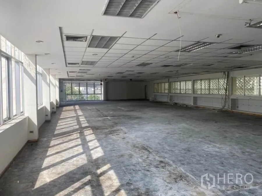 Office Space for rent in Khlong Toei, Bangkok - Sunlit open‑plan office floor with long rows of windows and a suspended grid ceiling.
