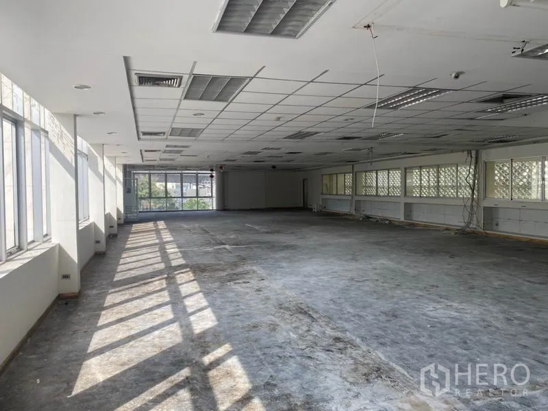 Office Space for rent in Khlong Toei, Bangkok - Sunlit open‑plan office floor with long rows of windows and a suspended grid ceiling.