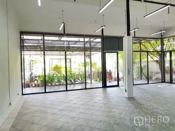 Office Space for rent in Chatuchak, Bangkok - Spacious office hall with full-height windows opening to a leafy patio.