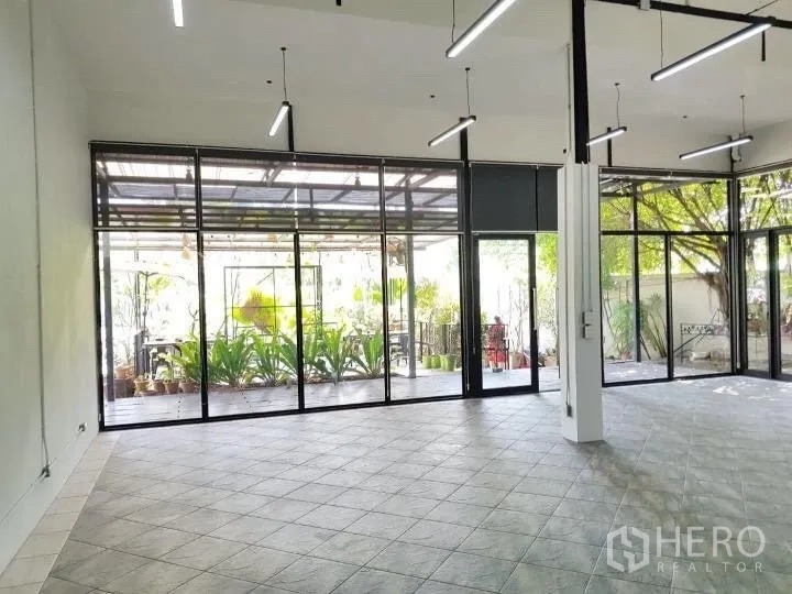 Office Space for rent in Chatuchak, Bangkok - Spacious office hall with full-height windows opening to a leafy patio.