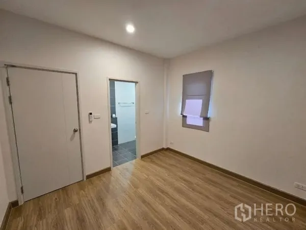Detached House for rent in Bang Phli, Samut Prakan - Bright bedroom with wood-look flooring and an ensuite bathroom doorway.