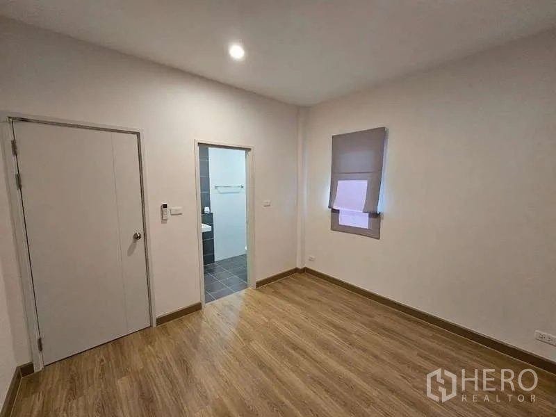 Detached House for rent in Bang Phli, Samut Prakan - Bright bedroom with wood-look flooring and an ensuite bathroom doorway.