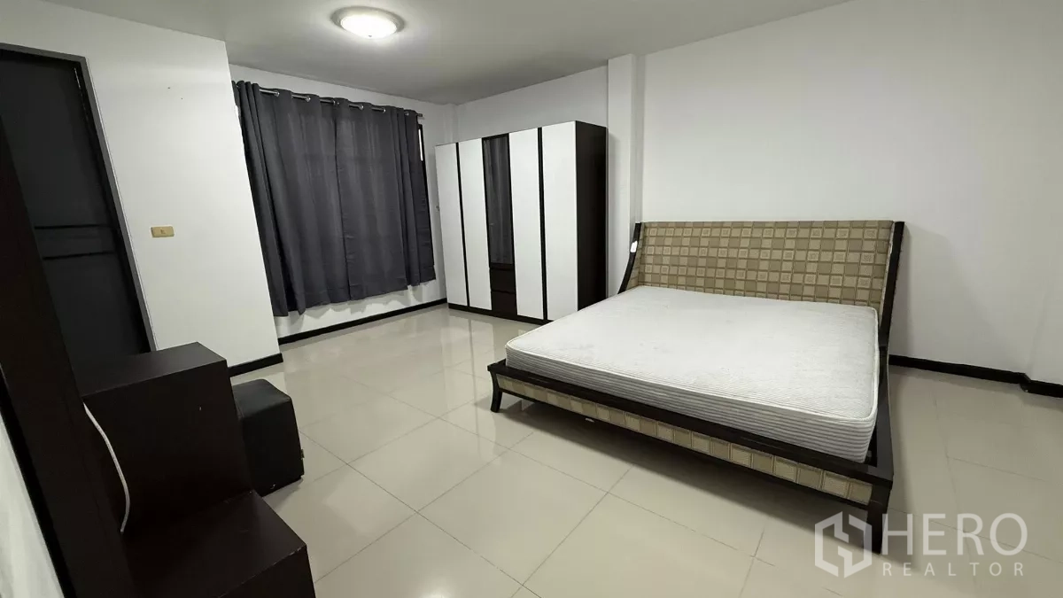Home Office for rent in Bang Na, Bangkok - Spacious master bedroom with large bedframe, wardrobe set, grey curtains and glossy tile flooring.