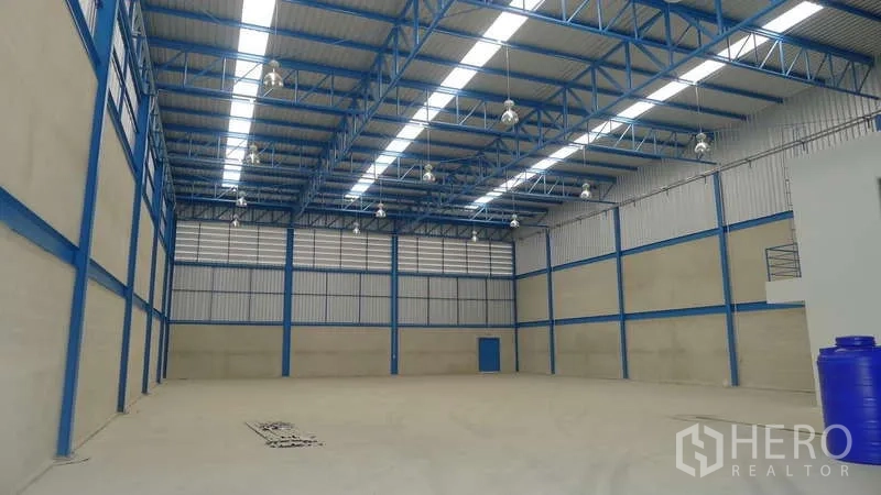Warehouse for rent in Bang Phli, Samut Prakan - High-clearance warehouse interior with blue steel trusses, skylights, and polished concrete floor.
