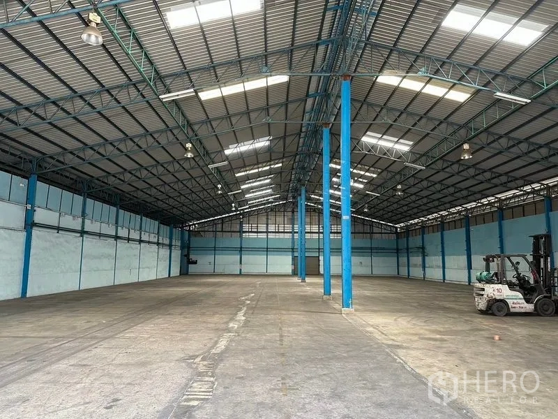 Warehouse for rent in Bang Pa-in, Phra Nakhon Si Ayutthaya - Open warehouse hall featuring blue steel columns, skylights and a forklift at the side.