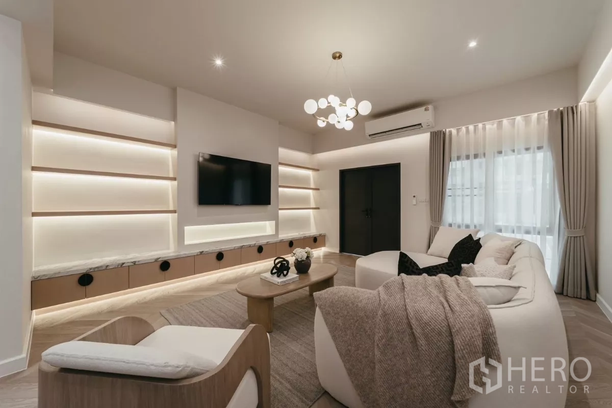 Townhouse for rent in Watthana, Bangkok - Media wall with built-in shelves, LED lighting and wall-mounted TV in living room.
