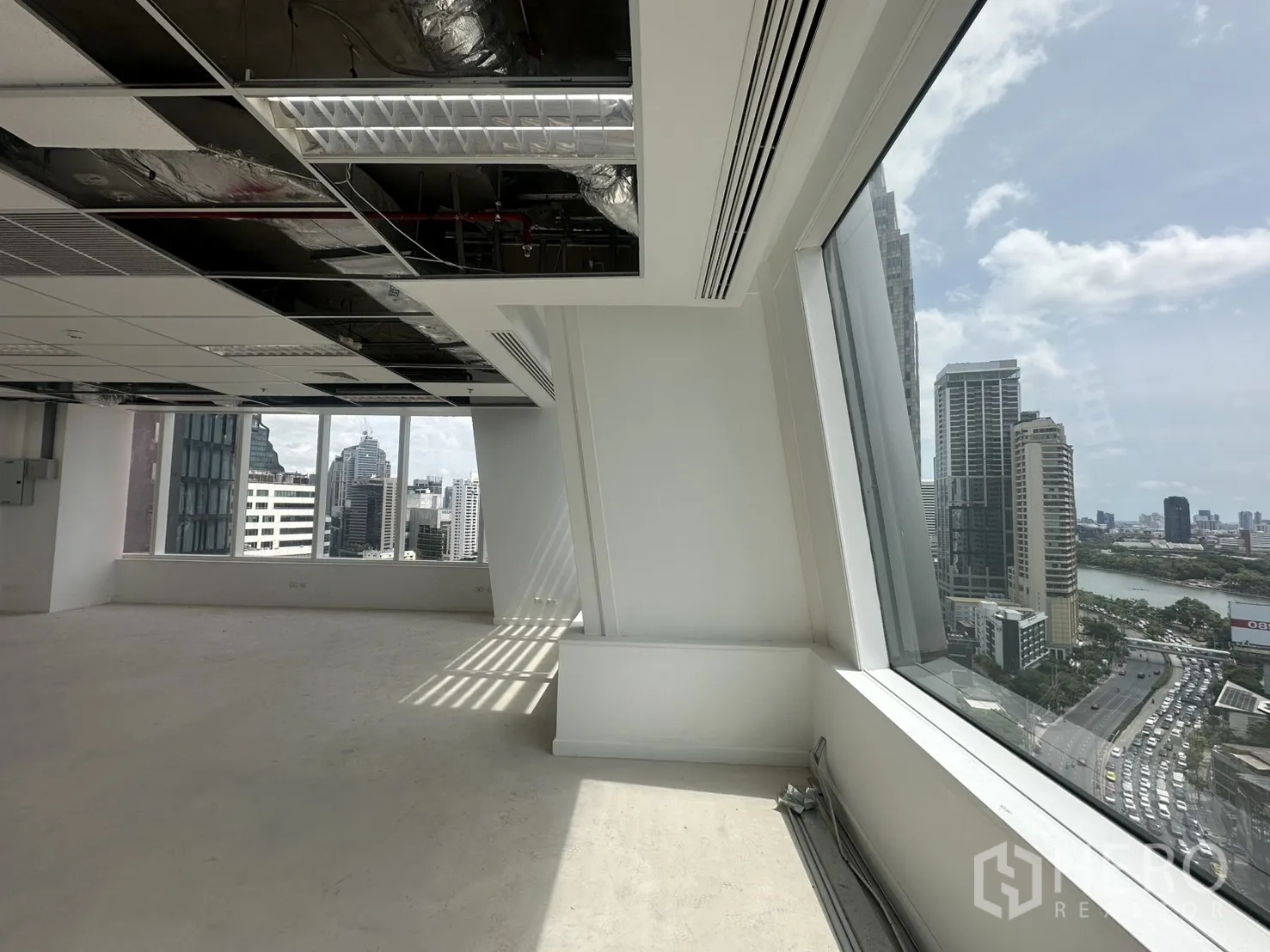 Office Space for rent in Watthana, Bangkok - Angled window bay showing city towers and a nearby park and lake.