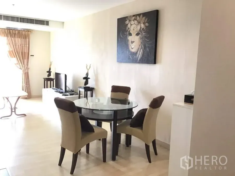 Condominium for rent in Watthana, Bangkok - Bright dining area with a round glass table, four upholstered chairs, wall art and light wood flooring.