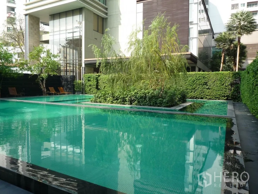 Condominium for rent in Khlong Toei, Bangkok - Landscaped outdoor swimming pool surrounded by greenery at a Bangkok condominium.