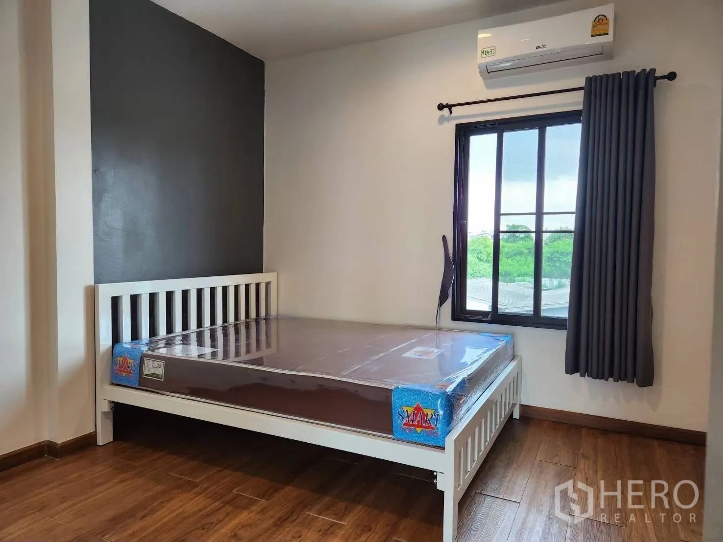 Townhouse for rent in Suan Luang, Bangkok - Guest bedroom with white bedframe, window and wood floors.