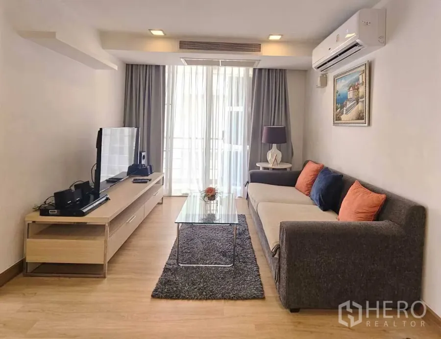 Condominium for rent in Watthana, Bangkok - Bright living room with long sofa, TV console, glass coffee table and balcony doors.