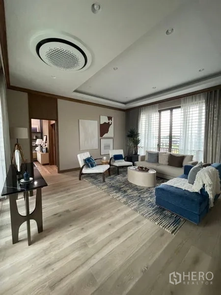 Detached House for sale in Bang Kapi, Bangkok - Spacious family room with wood flooring, large windows and a modern ceiling feature.