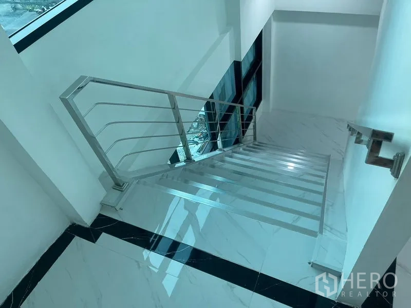 Home Office for rent or sale in Wang Thonglang, Bangkok - Daylit stairwell with steel railing and black-edged tiles.