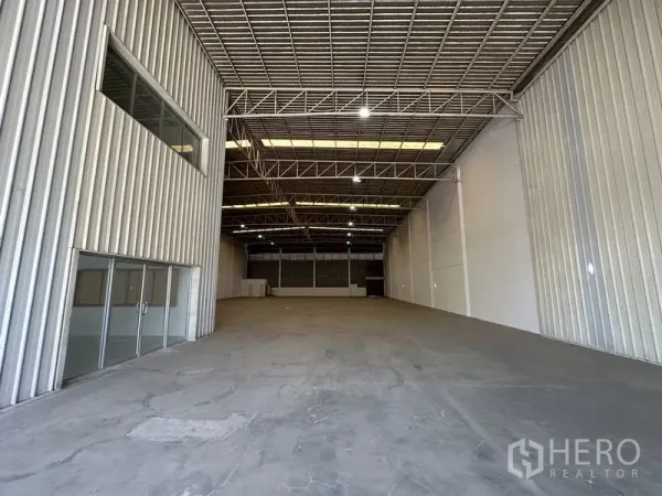 Factory for rent in Khlong Luang, Pathum Thani - Spacious warehouse interior featuring high steel truss roof, skylights, and polished concrete floor.