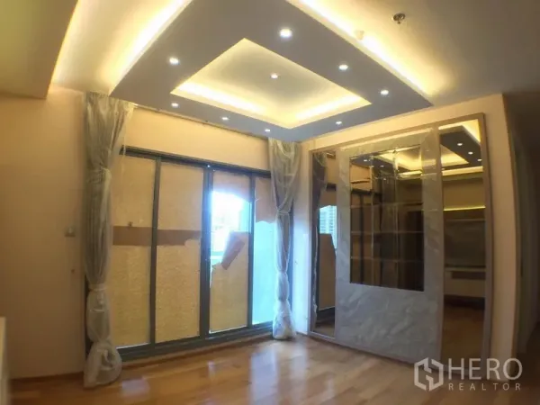 Condominium for rent in Watthana, Bangkok - Bright living room with recessed ceiling lights, sliding doors to the balcony and mirrored shelving.