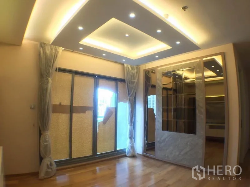 Condominium for rent in Watthana, Bangkok - Bright living room with recessed ceiling lights, sliding doors to the balcony and mirrored shelving.