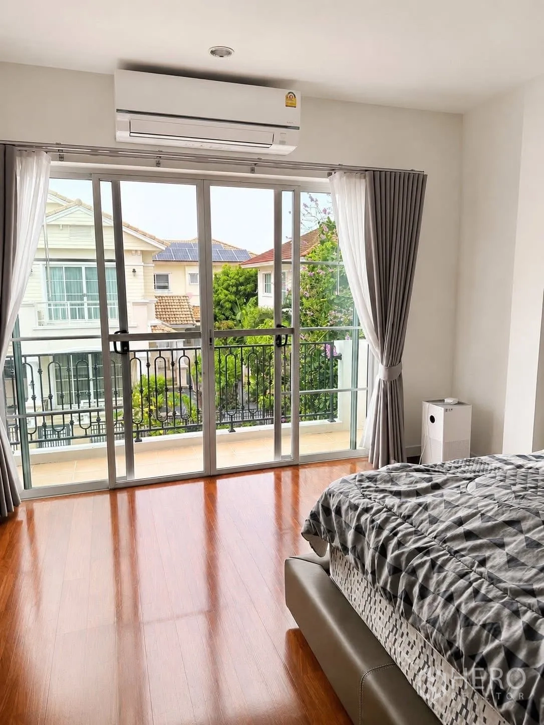 Detached House for rent in Prawet, Bangkok - Master bedroom with sliding glass doors opening to a balcony and greenery.