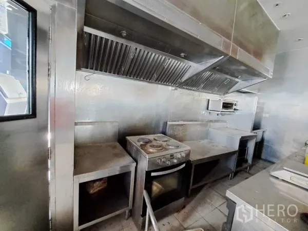Retail Space for rent in Khlong Toei, Bangkok - Stainless-steel commercial kitchen with exhaust hoods, oven and preparation counters.