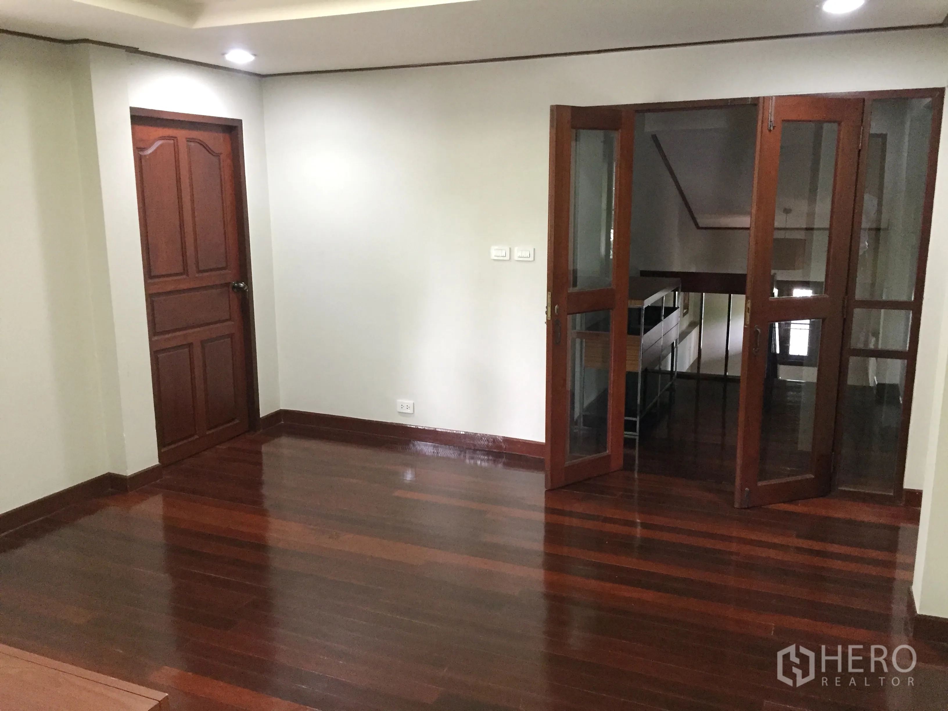 Detached House for rent in Khlong Toei, Bangkok - Upstairs landing with polished wooden flooring and glass doors to the hall.
