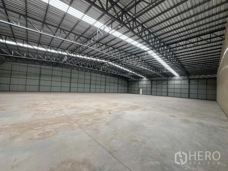 Warehouse for rent in Pak Kret, Nonthaburi - Spacious new warehouse interior with high steel truss roof, skylight strips, and polished concrete floor.