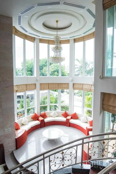 Detached House for rent or sale in Bang Kapi, Bangkok - Bright bay-window lounge with circular built-in sofa and chandelier overlooking garden.