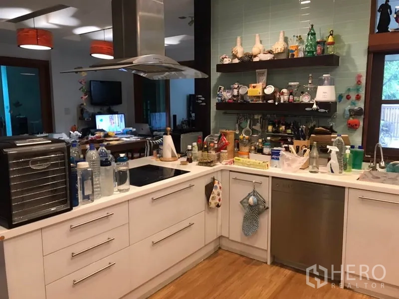 Detached House for sale in Lat Phrao, Bangkok - Modern U-shaped kitchen with white cabinetry, cooktop and island hood, open shelves and wood flooring.