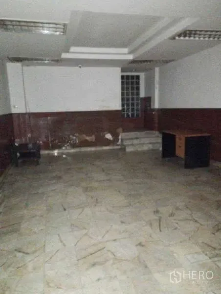Shophouse for rent in Watthana, Bangkok - Spacious room with marble-look flooring, step-up area and basic office desks.