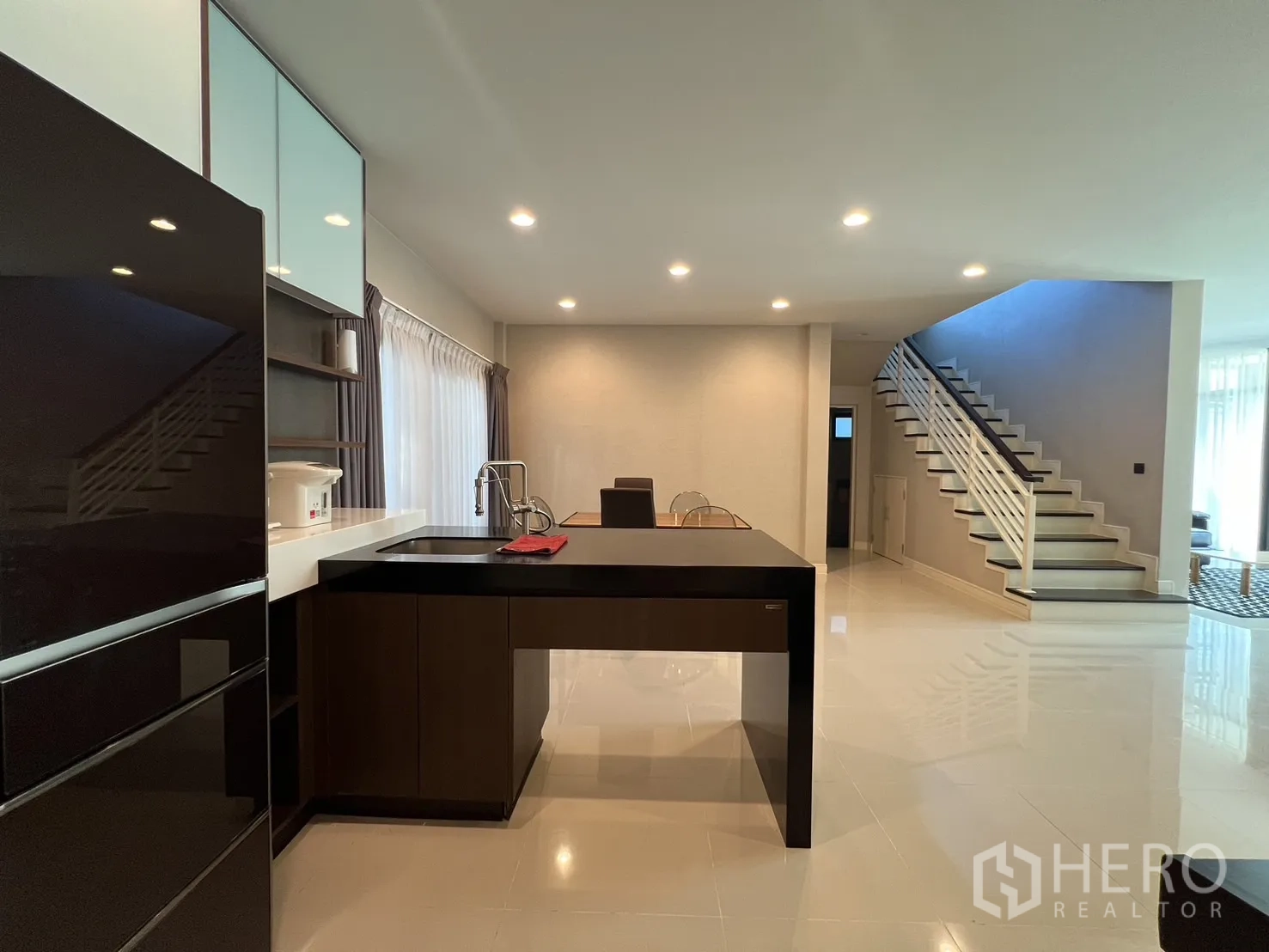 Detached House for rent or sale in Bang Kapi, Bangkok - Pantry island facing open staircase in a spacious, well‑lit ground floor.