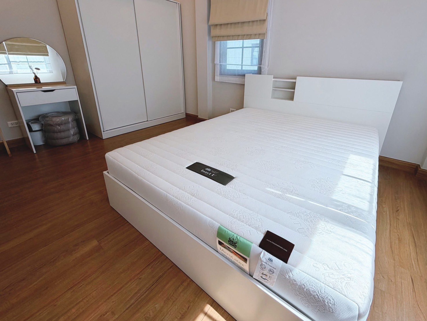 Detached House for rent in Bang Phli, Samut Prakan - Sunlit bedroom with white bed, sliding wardrobe, dressing table and wood floor.