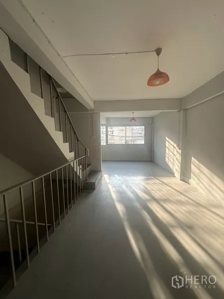 Shophouse for rent in Khlong Toei, Bangkok - Upper floor open space with window, pendant lights, and stair access.