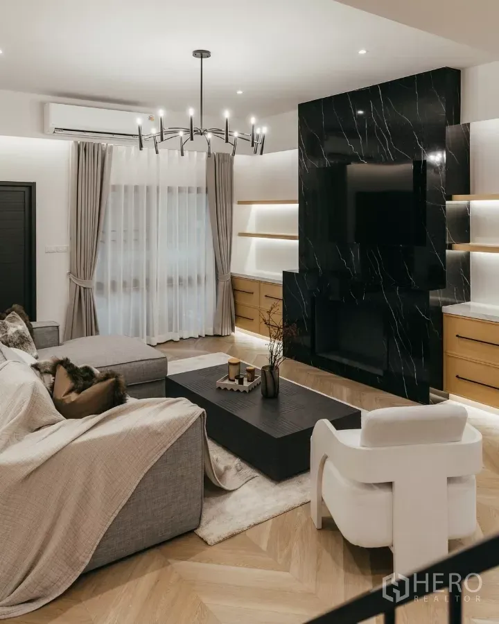 Townhouse for rent in Watthana, Bangkok - Modern Watthana townhouse living room with black marble TV wall, built-ins and chandelier.