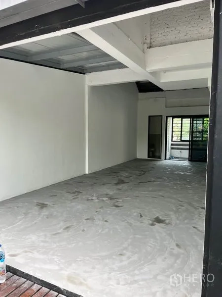 Retail Space for rent in Watthana, Bangkok - Open-plan shop space viewed from the entrance, showing deep layout, exposed beams, and sliding glass doors to a leafy terrace.