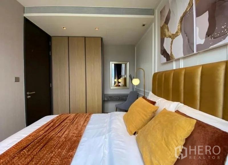 Condominium for rent - Cozy bedroom with mustard upholstered headboard, built‑in wardrobe and warm accent bedding.