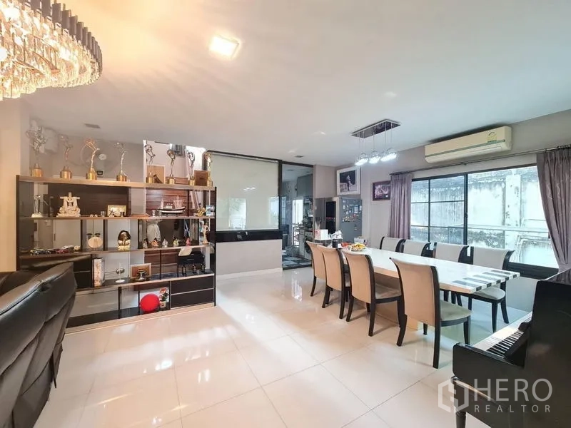 Detached House for sale in Prawet, Bangkok - Dining area with long table for eight, open shelving and air conditioning.