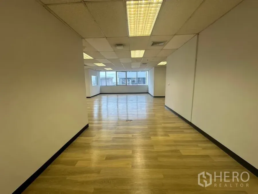 Office Space for rent in Phra Khanong, Bangkok - Open office corridor view showing wood floors, grid ceiling and windows drawing in daylight.