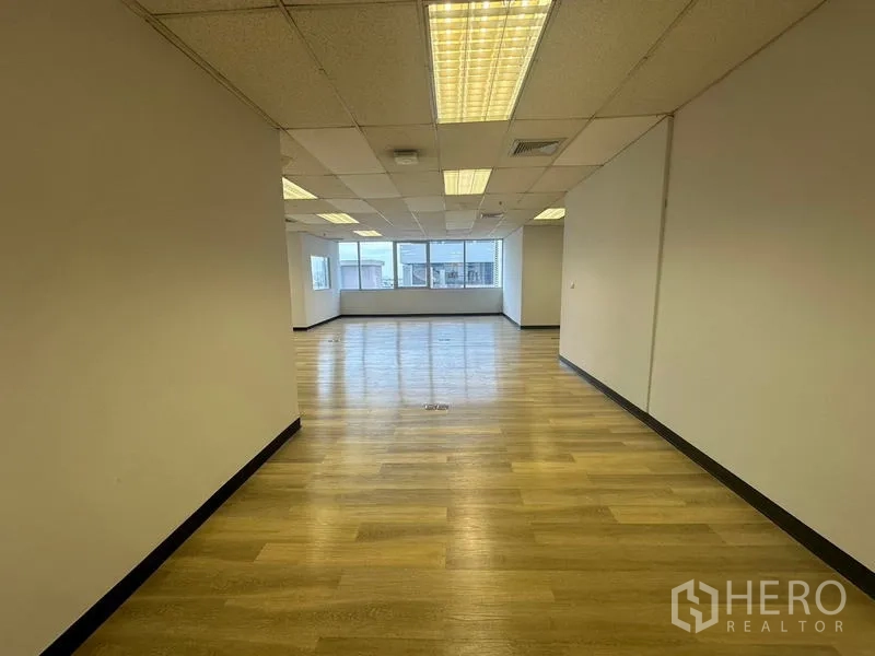 Office Space for rent in Phra Khanong, Bangkok - Open office corridor view showing wood floors, grid ceiling and windows drawing in daylight.