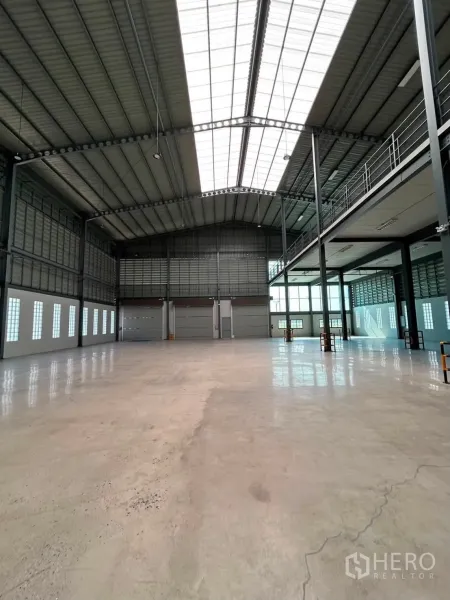 Warehouse for rent in Bang Phli, Samut Prakan - Open warehouse floor with high roof, skylights, and multiple roller shutter doors.