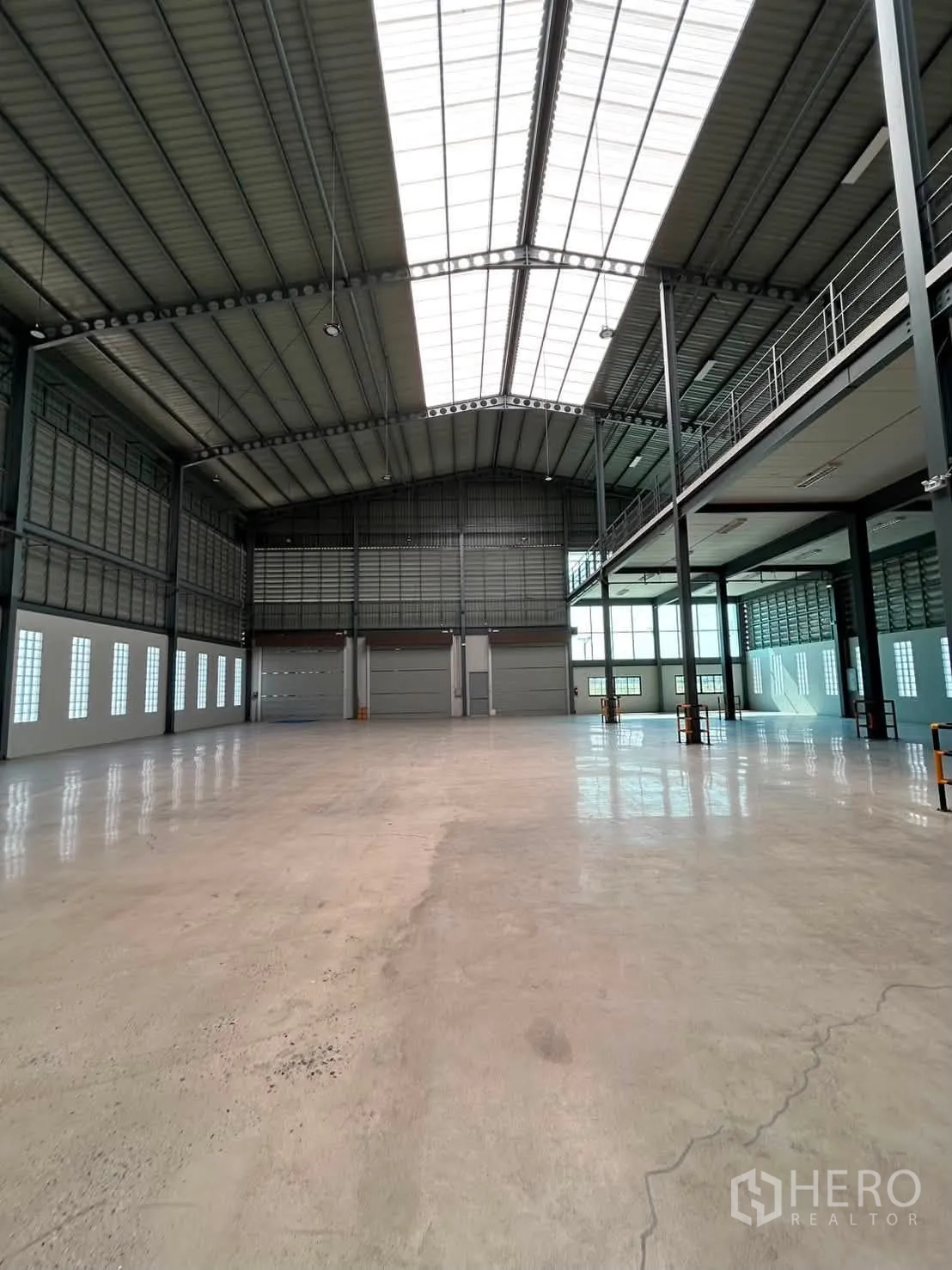 Warehouse for rent in Bang Phli, Samut Prakan - Open warehouse floor with high roof, skylights, and multiple roller shutter doors.