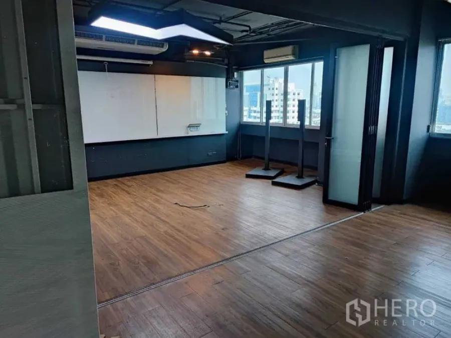 Office Space for rent in Watthana, Bangkok - Open-plan office with wood floors, large whiteboard wall, air-conditioning, and city-view windows.