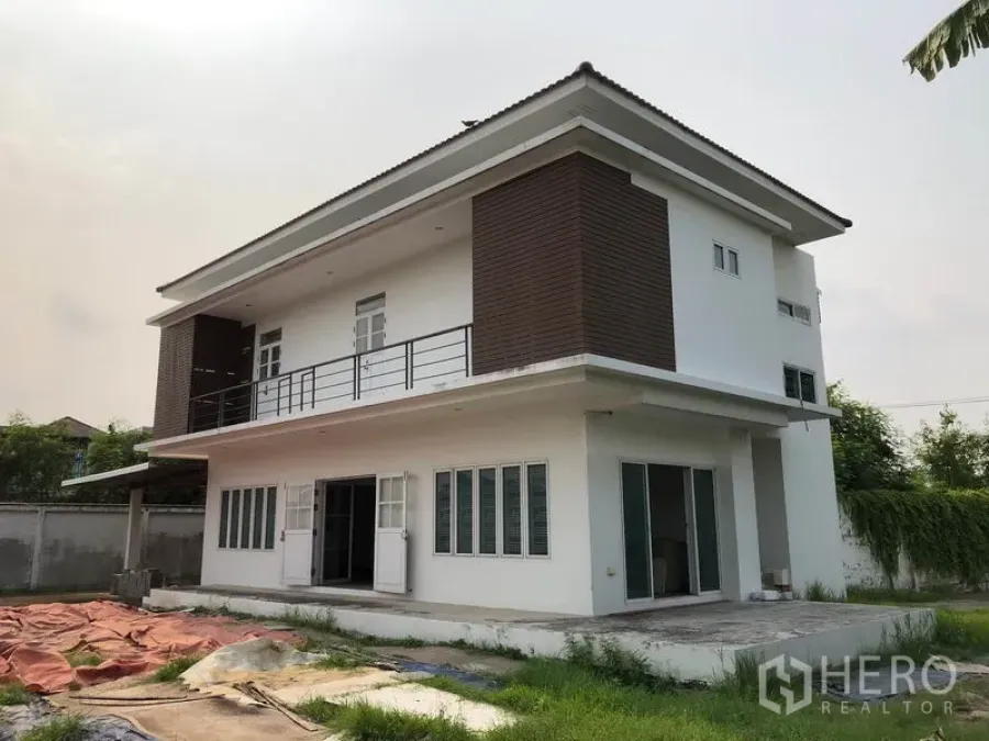Detached House for sale in Bang Khen, Bangkok - Modern two-storey detached house exterior with balcony, brown cladding, large windows and patio within a walled garden.