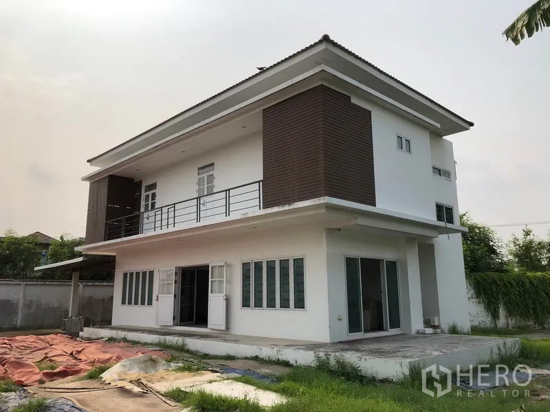 Detached House for sale in Bang Khen, Bangkok - Modern two-storey detached house exterior with balcony, brown cladding, large windows and patio within a walled garden.