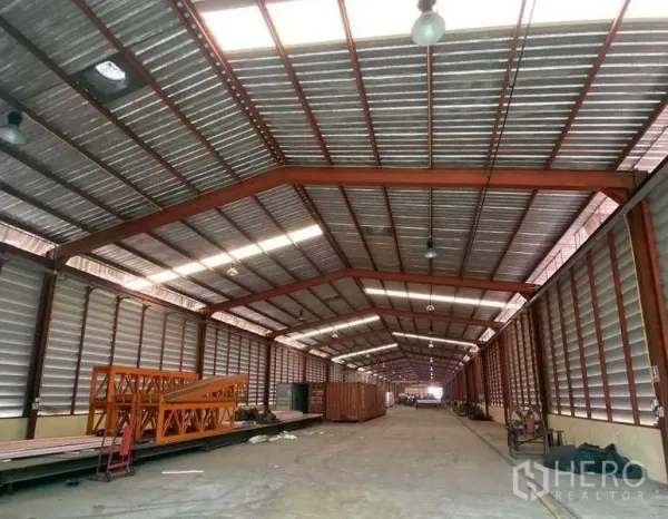 Factory for rent in Bang Kruai, Nonthaburi - Industrial shed showing red steel frame, long central aisle and ventilated side panels suitable for machinery or storage.