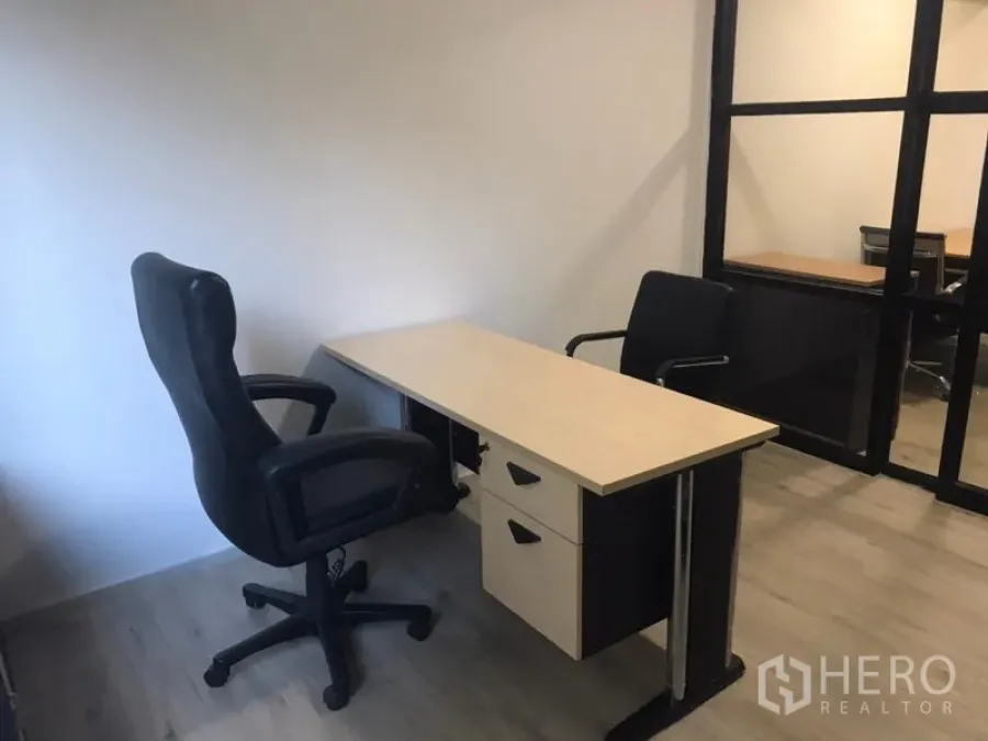 Office Space for rent in Khlong Toei, Bangkok - Private office with light wood desk, two black chairs and a glass-partitioned room.