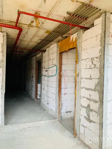 Home Office for rent - Rough corridor with block walls, door frames, and red fire-safety piping overhead.