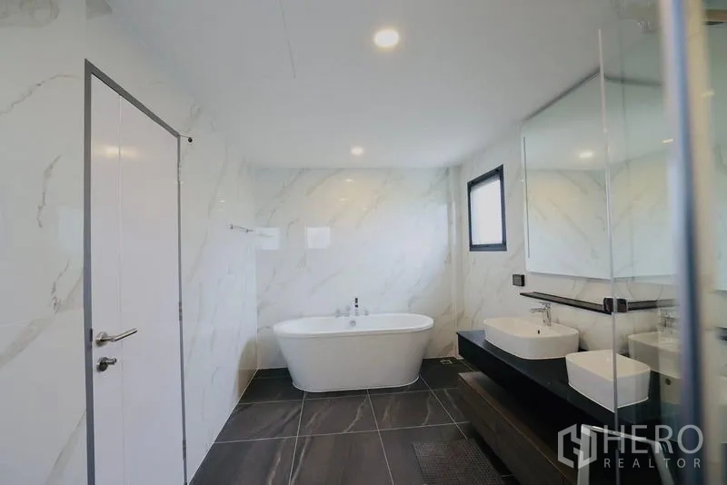 Detached House for rent in Bang Phli, Samut Prakan - Bathroom view showing a freestanding bathtub and twin basins on a dark counter.