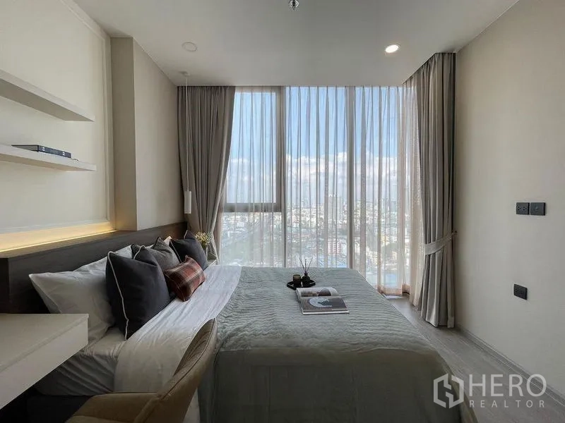 Condominium for rent in Pathum Wan, Bangkok - Bedroom with panoramic glazing, sheer curtains and wide Bangkok skyline views.