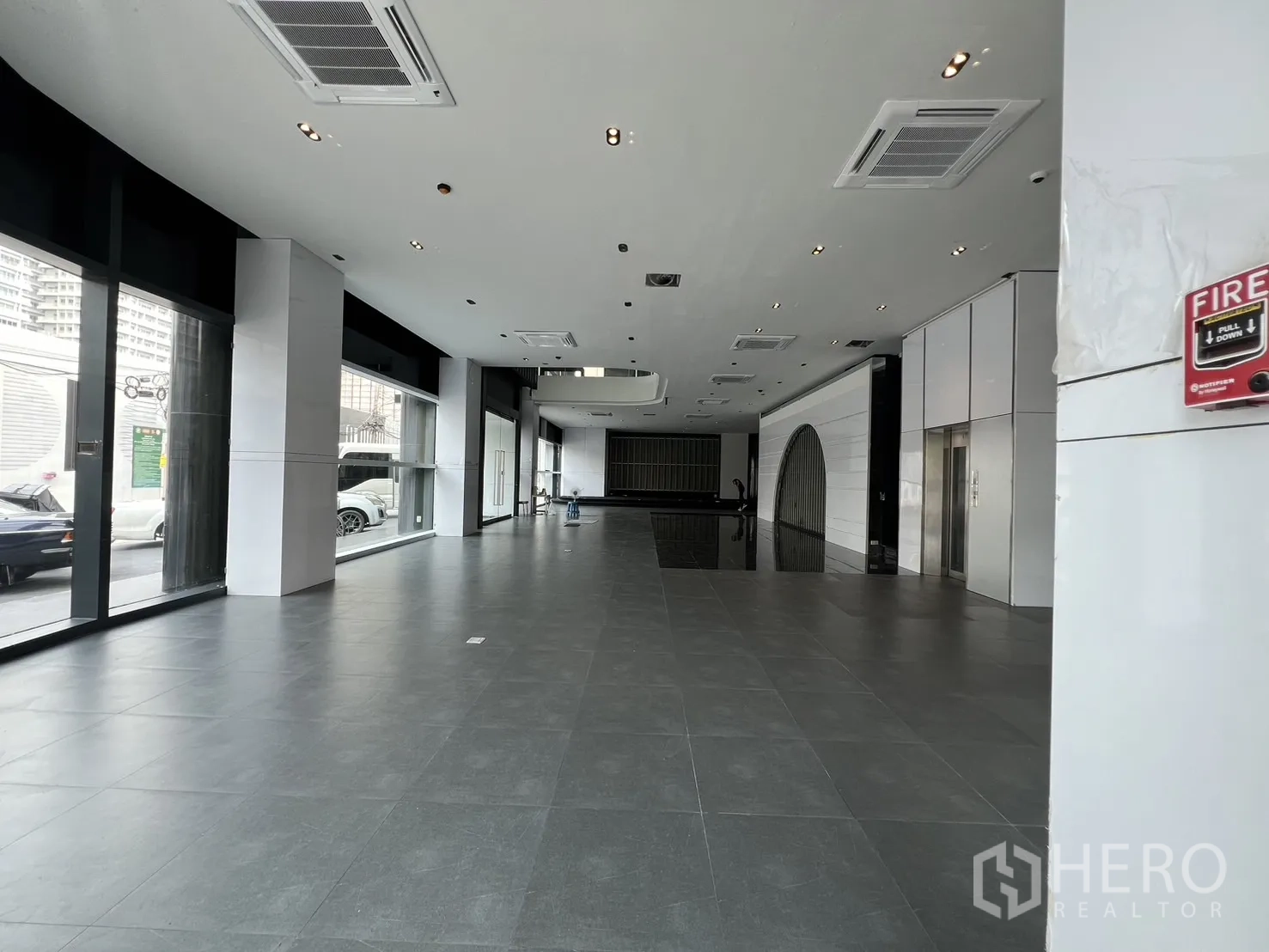 Retail Space for rent in Watthana, Bangkok - Spacious open-plan retail hall with floor-to-ceiling windows, gray tiles, and ceiling-mounted air-conditioning.