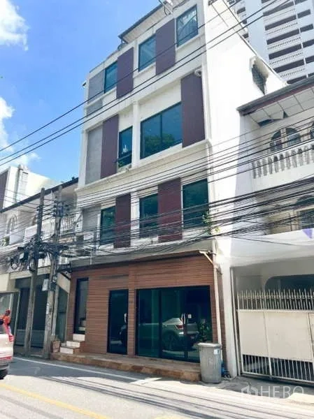 Retail Space for rent in Watthana, Bangkok - Four-storey shophouse exterior with ground-floor glass storefront on a quiet Bangkok street under blue sky.