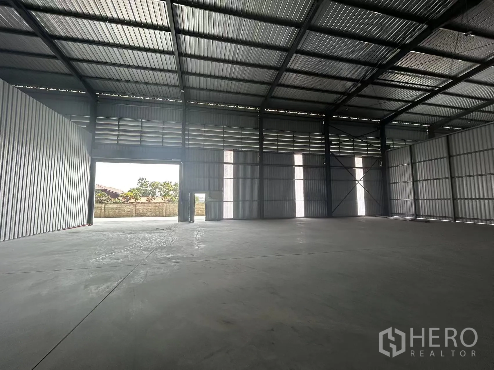Warehouse for rent in Lam Luk Ka, Pathum Thani - Open warehouse hall with a large roller door to the yard and clear-span floor area.