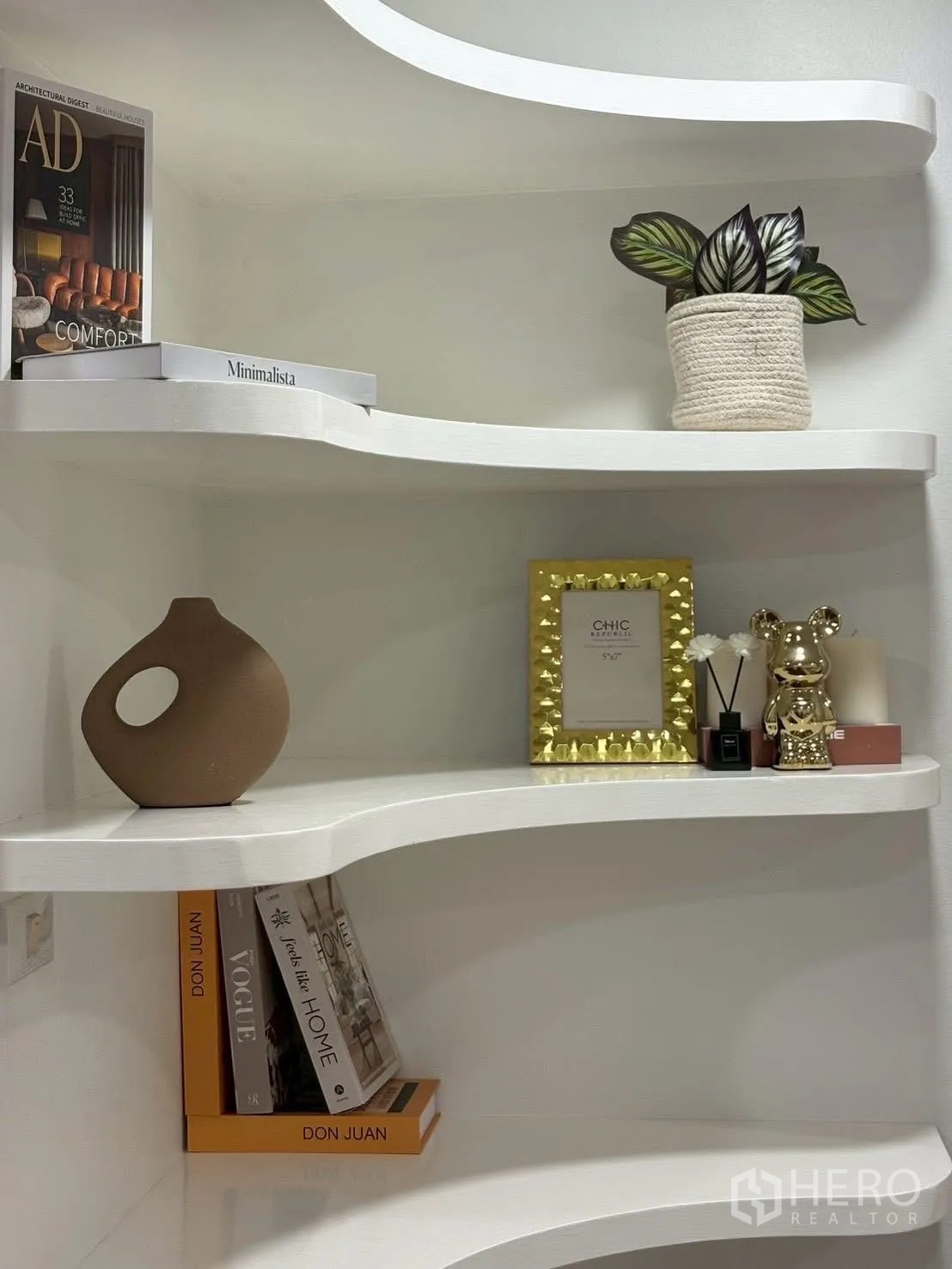 Townhouse for rent in Huai Khwang, Bangkok - Curved white wall shelves styled with books, vases, and plants.